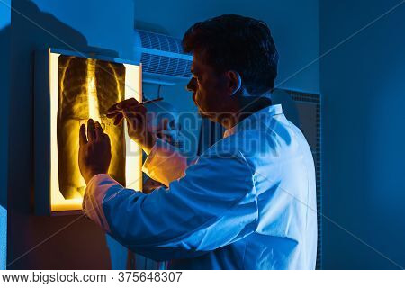 A Doctor In A White Robe Examines An X-ray Of The Lungs Or Chest In Neon Light. A Concept On The Top