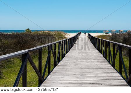 Conil De La Frontera, Spain, July 3, 2020: Wooden Walkway To The Beach In Summer With Tourists In So