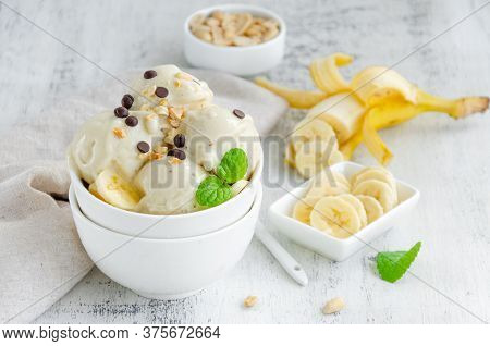 Homemade Vegan Banana Ice Cream In A Bowl With Peanuts And Chocolate On A Wooden Background. Healthy