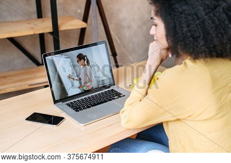 Webinars, Lectures Online. A Biracial Woman In Office Is Watching Online Classes, Female Teacher On 