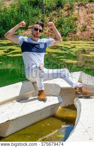 Young Man In White Pants And Modern Styling Posing In The Freshwater Pond Of Clot De La Mare De Deu 