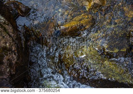 Stream Flows Placidly Among The Green Meadows On The Alpine And Granite Rocks Of The Lagorai Near La