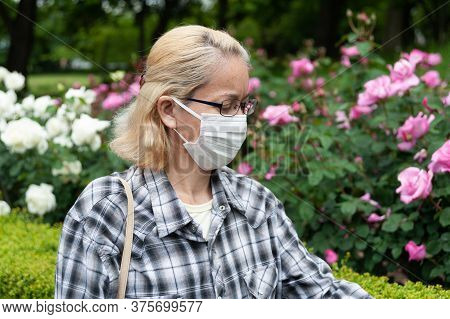 Portrait Of Middle Aged Mixed Race Blonde Woman With Eyeglasses Wearing White Surgical Mask. Protect