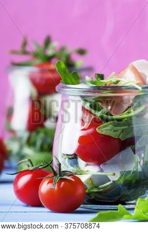 Summer Salad With Arugula, Soft Cheese, Cherry Tomatoes And Prosciutto In Glass Jars, Festive Backgr