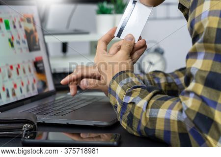 Asian Man Holding Credit Card And Typing Information On Internet With Laptop At Home, Online Shoppin