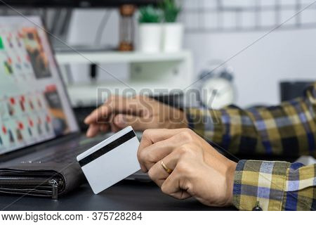 Asian Man Holding Credit Card To Online Shopping With Laptop Computer And Entering Security Code, In