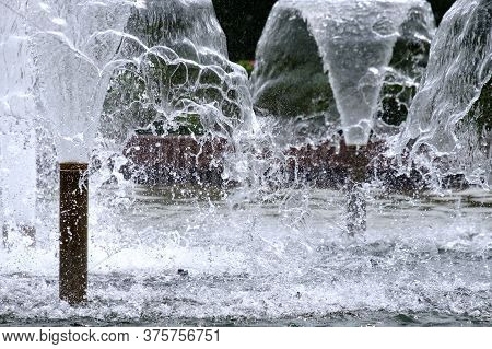 Selective Focus On Spray Of Urban Fountain And Blurred Background. A Fountain With Splashes And Drop