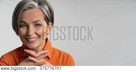 Mature Woman Broadly Smiling With Fingers Crossed. Happy Female Model In Orange Shirt. Close Up Port