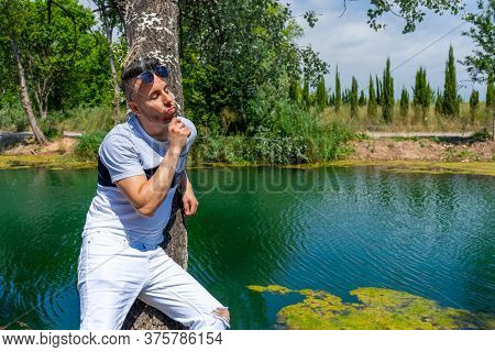 Young Man In White Pants And Modern Styling Posing In The Freshwater Pond Of Clot De La Mare De Deu 