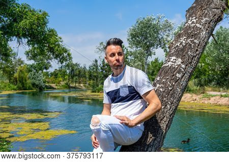 Young Man In White Pants And Modern Styling Posing In The Freshwater Pond Of Clot De La Mare De Deu 