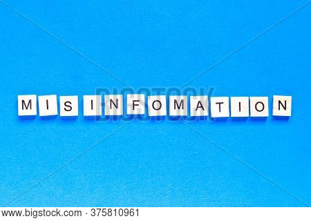 Mystification Written In Wooden Letters On A Blue Background, Top View, Flat Layout, Deception, Fake