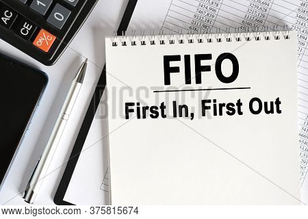 On The Table Lies A Smartphone, A Calculator And A Notebook With The Inscription- Fifo. First In, Fi