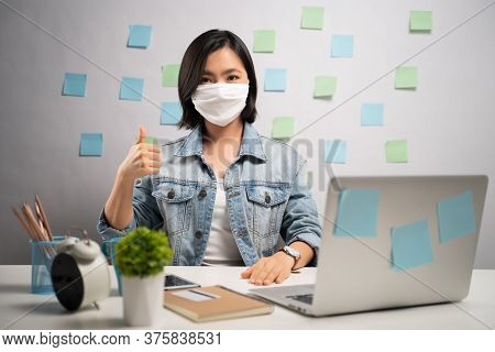 Asian Woman Wearing Protective Face Mask Happy And Showing Thumb Up At Home Office. Wfh. Work From H