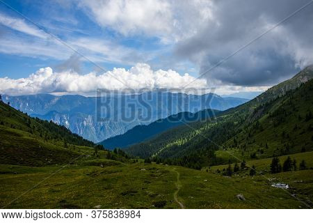 Granite Peaks With Path Rise From Green And Red Flowery Meadows In The Splendid Setting Of The Lagor