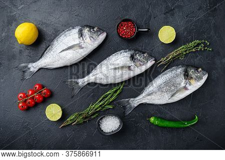 Dorado Or Seabream Fish Set With Herbs For Grill Uncooked  On Black Stone Textured Table Top View.