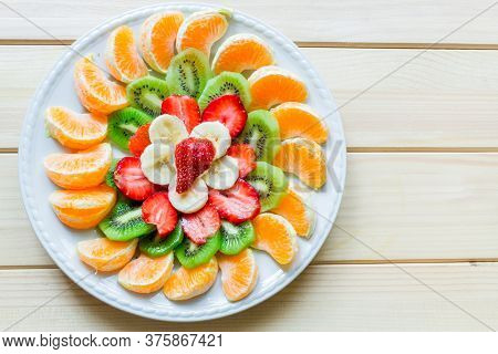 Platter Ornamanted With Orange Slices, Kiwi, Bana Slices And Strawberries On Wood Table With Negativ
