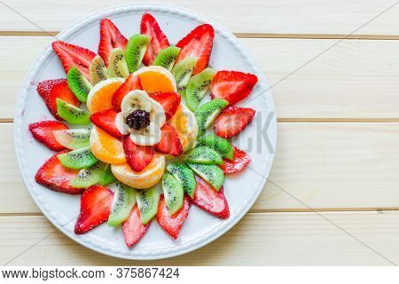 Platter Ornamanted With Orange Slices, Kiwi, Bana Slices And Strawberries On Wood Table With Negativ