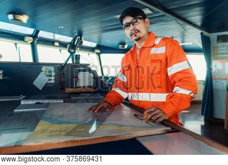 Filipino Deck Officer On Bridge Of Vessel Or Ship. He Is Plotting Position On Chart