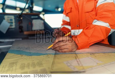 Filipino Deck Officer On Bridge Of Vessel Or Ship. He Is Plotting Position On Chart
