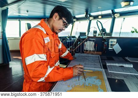 Filipino Deck Officer On Bridge Of Vessel Or Ship. He Is Plotting Position On Chart