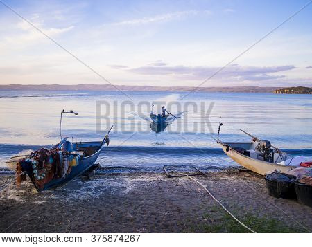 Fisherman With Traditional Boat Returns To The Coast After A Fishing Trip, Bolsena Lakeshore, Viterb