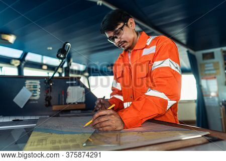 Filipino Deck Officer On Bridge Of Vessel Or Ship. He Is Plotting Position On Chart