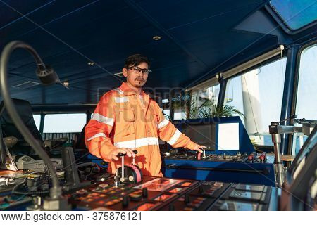 Filipino Deck Officer On Bridge Of Vessel Or Ship. He Is Speaking On Gmdss Vhf Radio
