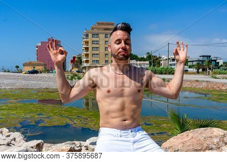 Young Man In White Pants And Modern Styling Posing In The Freshwater Pond Of Clot De La Mare De Deu 