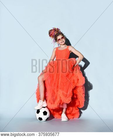Happy Smiling Girl With Colorful Dreadlocks In Sneakers Stands With Soccer Ball Under Foot Holding L