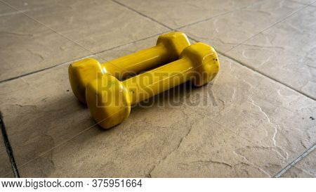 Pairs Of 1 Kilogram Yellow Mini Dumbbells On The Floor.