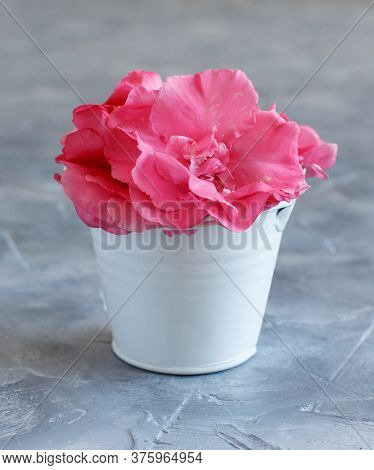 White Bucket Full Of Pink Flowers On A Grey Table Close Up