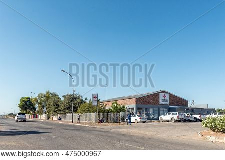 Prieska, South Africa - Mar 1, 2023: A Street Scene, With A Medical Centre, People And Vehicles, In 