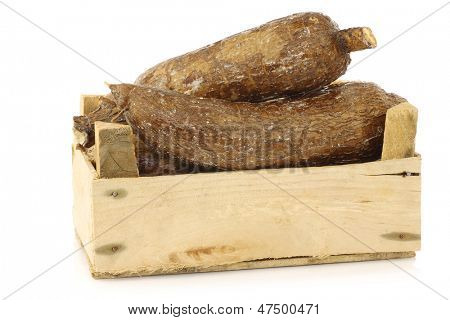 mazzo di radici di manioca in una cassa di legno su sfondo bianco