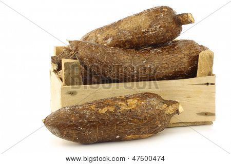 mazzo di radici di manioca in una cassa di legno su sfondo bianco