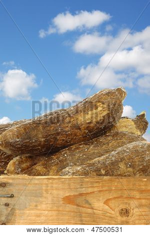 radici di manioca intero in una cassa di legno contro un cielo blu con nuvole