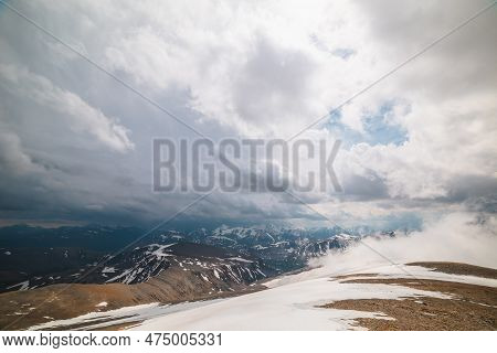 Awesome Top View Through Clouds To High Snowy Mountains. Scenic Landscape With Beautiful Snow Mounta