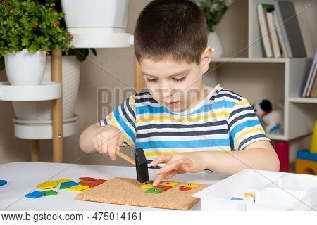 A Preschool Child Plays With A Mosaic, Builds Figures On A Board, Hammering Nails With A Hammer On M