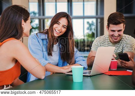 Group Of Smiling Young Students Using A Laptop For Research And Do The Homeworks Together At Highsch