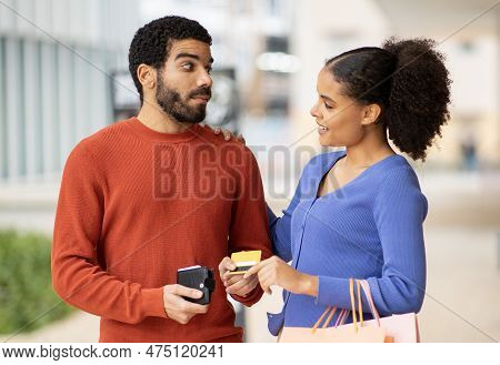 Stingy Husband Giving Credit Card To Wife Shopping Outdoor
