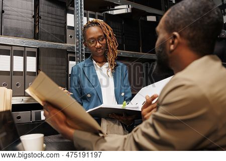 African American Police Archive Worker Holding Crime Case Folder And Talking With Policeman. Prosecu