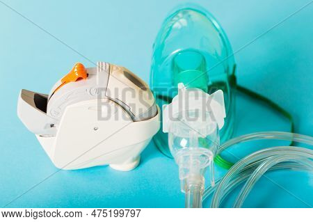 A Respiratory Mask And Inhaler Are On A Blue Background. Bronchitis, Asthmatic Health Equipment.