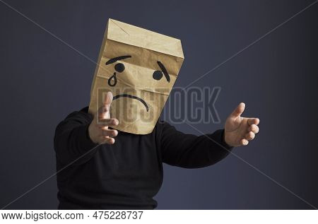 A Sad Man In A Black Turtleneck With A Bag On His Head, With A Drawn Crying Emoticon, Cries And Asks