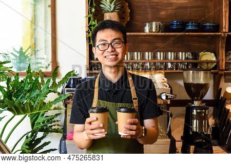 Vietnamese Smiling Waiter Holding Paper Cups With Coffee In A Cafe