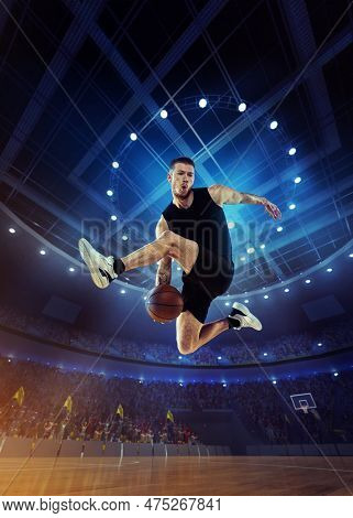 Dynamic Image Of Young Man, Professional Basketball Player In Motion, Jumping With Ball During Match