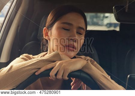 Asian Woman With Her Hands On The Steering Wheel Feeling Exhausted, Stressed With Work, Thinking Abo