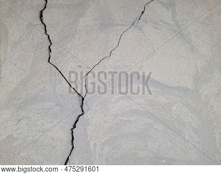 Cracked Concrete Wall Covered With Gray Cement Mortar. Destruction Caused By An Earthquake. Large Un