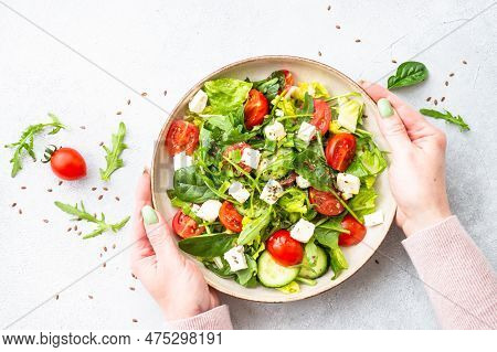 Spring Salad In Craft Plate. Spinach, Arugula, Tomatoes And Feta With Olive Oil. Top View On White.