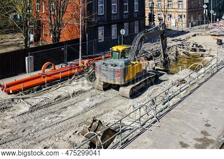 Underground Pipeline Replacement Site With Dewatering System On City Street, Excavator Digs Deep Tre