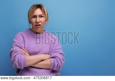 Doubting Blond Woman Looking Contemptuously At Camera On Blue Background With Copy Space