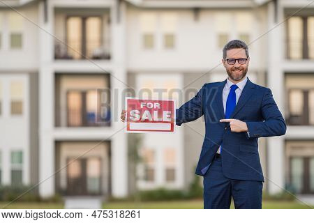 Handsome Real Estate Agent Holding Banner House For Sale. House With Land And Insurance. Man Real Es